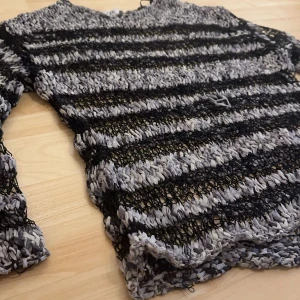 Randig stickad tröja från Zara - Säljer en unik stickad tröja från Zara i svart och grått. Tröjan har ett randigt mönster och är långärmad med en luftig design. Perfekt för att lägga till en cool touch till din outfit. 🖤 Vill nämna att vissa trådar av tröjan hänger lite, som ni ser på sista bilden. Men den är inte sönder.