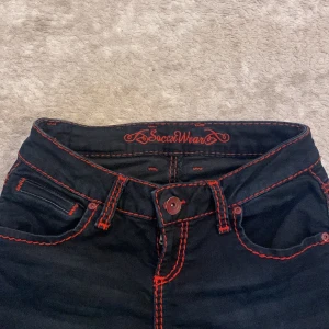 Svarta jeans med röd söm från Soccx - Snygga svarta jeans från Soccx med iögonfallande röda sömmar. Klassisk femficksdesign och knappgylf. Perfekta för en cool och avslappnad stil.