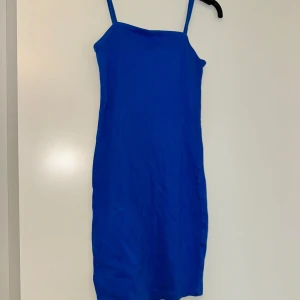 Blå klänning från A.M.S.D - Snygg blå klänning med smala axelband från A.M.S.D. Perfekt för sommarens varma dagar. Klänningen har en enkel och stilren design som gör den lätt att matcha med olika accessoarer.
