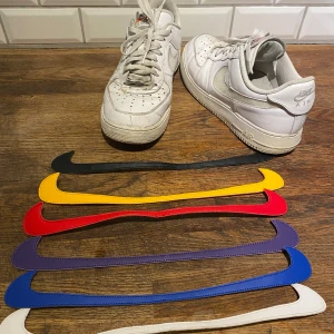 Nike Air Force ”Swoosh” Edition - Säljer ett par vita Nike Air Force Swoosh. Skorna är ett par helt vanliga Nike Air Force bara att loggan sitter med kardborre så att man enkelt kan byta färg. Använt skick. Låda skickas med.