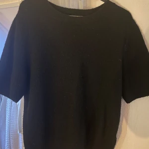 Svart tröja med korta ärmar - Säljer en stilren svart tröja med korta ärmar. Perfekt för en minimalistisk look. Tröjan har en enkel design och är lätt att matcha med olika outfits.