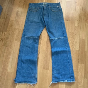 Bootcut Blå jeans med flare  - Säljer ett par blå jeans med fransiga detaljer vid knäna och bensluten. De har en klassisk femficksdesign och har en bootcut/flared passform. Skriv vid frågor/köp 