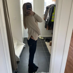 Beige stickad tröja - Fin stickad tröja från H&M. Om man tittar noga på bilden kan man se att längst ut på ärmarna är har den en slitts, samma på båda sidorna av tröjan (det ska vara så)