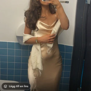 Champagnefärgad sidenklänning - Elegant champagnefärgad långklänning i siden med en slits framtill och öppen rygg. Klänningen har smala axelband och en vacker, flytande passform som passar perfekt för festliga tillfällen. Inga defekter och skriv vid frågor❣️