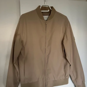 Beige bomberjacka från Jack & Jones - Snygg beige bomberjacka från Jack & Jones. Perfekt till hösten då den är tillräckligt varm och vattentät. 