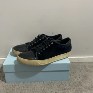 Svarta sneakers från Lanvin - Snygga svarta sneakers från Lanvin med snörning och en robust gummisula. Skorna har en stilren design med en diskret logotyp på sulan. Perfekta för en casual look.
