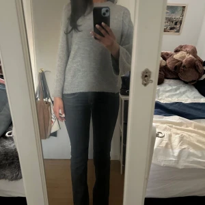 Grå stickad tröja - Säljer en mysig grå stickad tröja med rund hals och långa ärmar. Perfekt för kyligare dagar och enkel att matcha med olika outfits. Tröjan har en avslappnad passform och ribbade kanter vid ärmslut och nederkant.