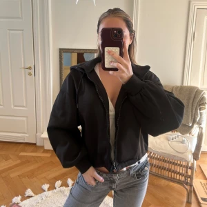 Svart jacka med luva och dragkedja - Säljer en tunn svart jacka med dragkedja och huva. Jackan har en croppad passform och långa ärmar. Perfekt för en avslappnad stil. Köpt från Zara nypris ca 500!