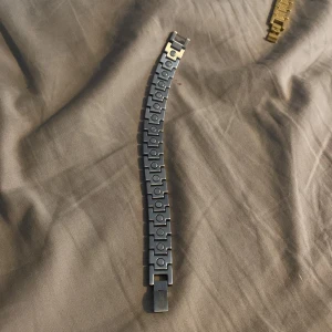 Lacoste armband - Stilrent silverfärgat armband med ett unikt rutmönster. Armbandet har en säker låsmekanism och en elegant design som passar perfekt för att lyfta vilken outfit som helst.