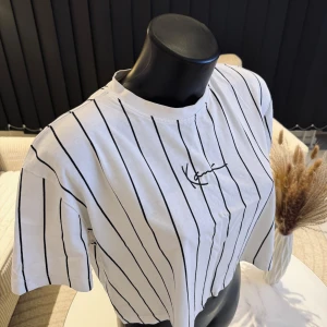 Vit randig t-shirt med tryck - Snygg vit t-shirt med svarta ränder och ett stilrent tryck på bröstet. Perfekt för en avslappnad stil. Passar bra som oversize modell. Jag rekommenderar den varmt.🌸👌