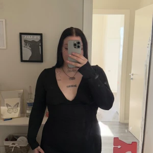 Svart klänning från Shein - Snygg svart klänning från Shein med v-ringning och långa ärmar. Klänningen har en figurnära passform och är tillverkad i polyester och elastan för en bekväm känsla. Perfekt för en stilren look.