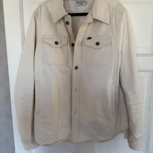Off white overshirt från Tiger of Sweden - Säljer en stilren beige overshirt från Tiger of Sweden i 100% bomull. Jackan har långa ärmar och knappar framtill samt på bröstfickorna. Fickor finns på bröstet och på sidorna.Perfekt för en avslappnad look. Endast använd ett fåtal gånger