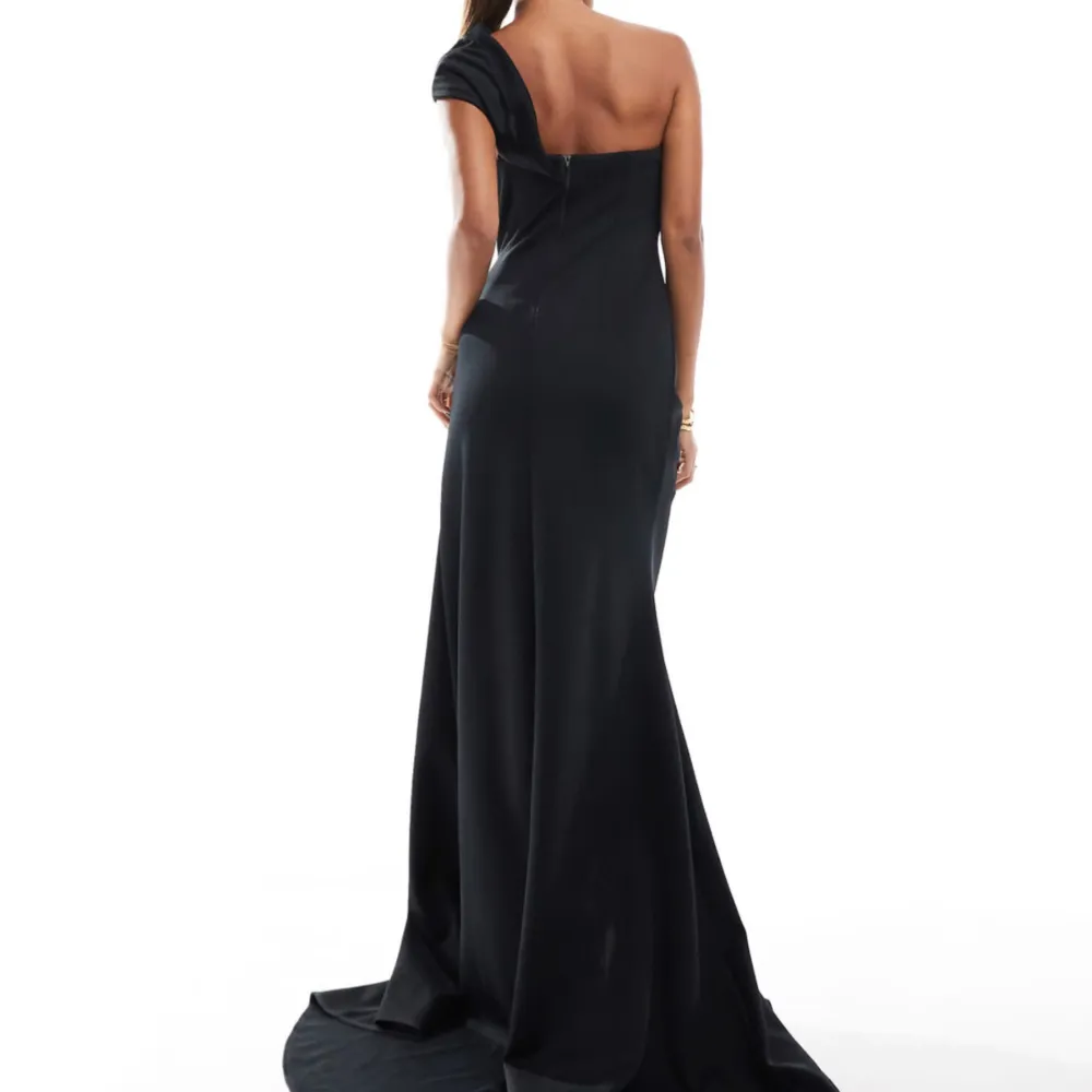 Elegant svart oneshoulder klänning med en stor rosdetalj på axeln och slits. Storlek 36. Slutsåld på ASOS. Ord pris 1349kr.. Mekot.