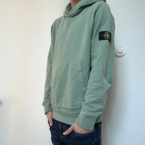 Stone Island hoodie - Säljer en riktigt snygg och sommrig hoodie från Stone Island som är i en ljusare grön färg. Tröjan är nyskick och använd ett frågar gånger. Hoodien passar perfekt på dig som är ca 164cm