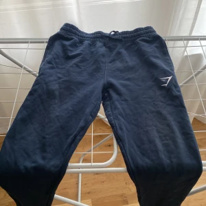 Svarta mjukisbyxor från Gymshark - Säljer ett par svarta mjukisbyxor från Gymshark. Byxorna har en elastisk midja med snörning och en liten logotyp på benet. Perfekta för en avslappnad dag eller träning. Använda Max 2/3 ggr!