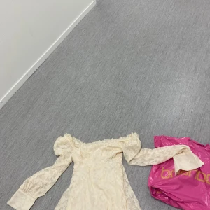 Beige blommig klänning från Boohoo - Säljer en helt ny klänning med prislappen en romantisk beige klänning från Boohoo med blommigt mönster. Klänningen har offshoulder-design och långa ärmar med volangdetaljer. Perfekt för sommarens fester!