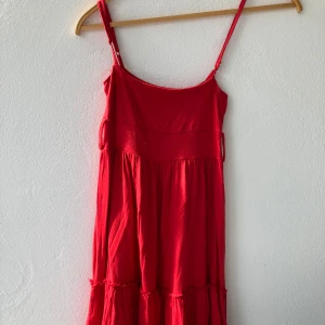 Röd klänning från Gina Tricot - Snygg röd klänning från Gina Tricot med smala axelband och en luftig passform. Perfekt för varma dagar med sin lätta design och härliga färg. Klänningen har en enkel och stilren look som passar till många tillfällen.