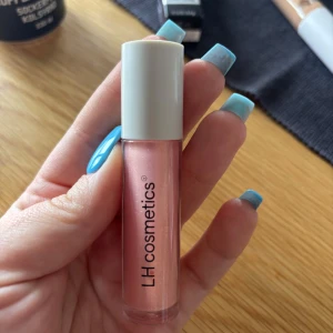 Läppglans från LH Cosmetics - Snyggt läppglans i en skimrande rosa nyans från LH Cosmetics. Perfekt för att ge läpparna en glansig finish. Kompakt och lätt att ta med sig i väskan.