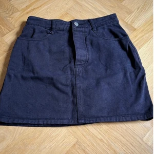 Svart jeanskjol från J. Galt stl S - Snygg svart jeanskjol från J. Galt med klassisk design. Kjolen har en knapp och dragkedja framtill samt praktiska fickor både fram och bak. Perfekt för en stilren look. Stl S