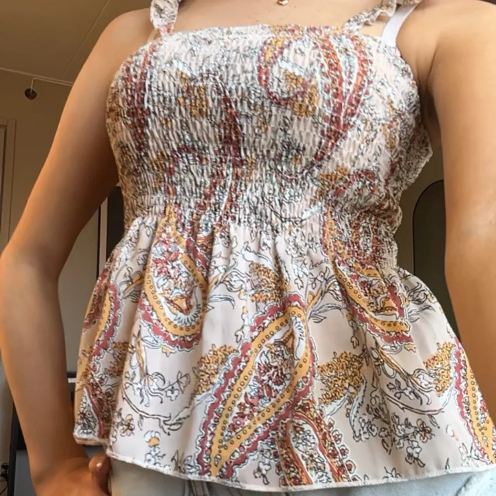 Säljer en söt topp med smockdetaljer och paisleymönster i rött, orange och beige. Toppen har  luftig passform som är perfekt för varma dagar. Hör av er vid frågor!!💞🌸. Yläosat.