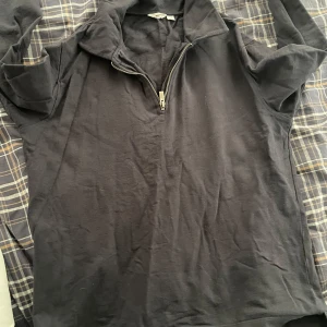 Svart långärmad tröja med dragkedja - Säljer en svart långärmad tröja från dobber med dragkedja vid halsen. Perfekt för en avslappnad stil. Tröjan har en enkel design och är tillverkad i ett mjukt material.