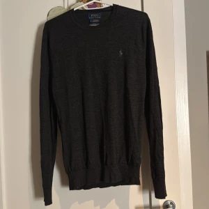 Svart tröja från Polo Ralph Lauren - Säljer en stilren svart tröja från Polo Ralph Lauren i MERINOULL!!!!!!!!!Tröjan har en slim fit passform och långa ärmar. Perfekt för en elegant och bekväm look. Den är köpt på herr avdelningen och tar ingen skriven storlek på sig. Men skulle gissa M
