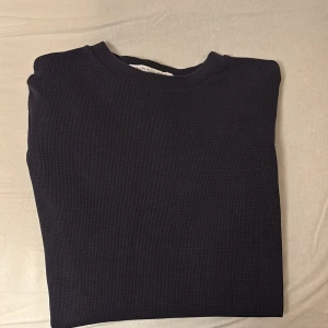 Mörkblå tröja från Calvin Klein Jeans - Säljer en stilren mörkblå tröja från Calvin Klein Jeans. Tröjan har en diskret ribbad struktur och en logga på ärmen. 