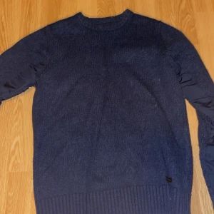 Mörkblå stickad tröja från Peak Performance - Säljer en snygg mörkblå stickad tröja från Peak Performance. Tröjan har långa ärmar och en ribbad nederkant som ger en stilren look. Perfekt för kyligare dagar.