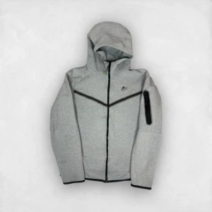 Grå hoodie från Nike - Säljer en grå nike tech hoodie, defekter finns men inte så man störs eller märks. vid snabb affär kan jag sänka pris