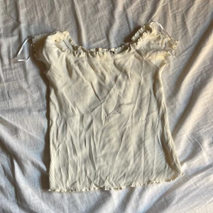 Vit ribbad topp - Säljer en söt vit ribbad topp med korta ärmar och volangdetaljer vid hals och ärmslut. Perfekt för sommardagar! 💫 ser liten ut men passar i S också, inte genomskinlig, priset kan diskuteras med kunden😁