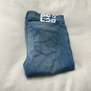 Jacob Cohën Jeans - Tja! Söljer nu dessa Jacob Cohën jeans! De är ljusblåa och har många fina detaljer (se bild). Längst ner så är den sydd ihop för att den var för lång, men det ser ut som vanligt, och det märks inte. Utöver det så är skicket 10/10, inga defekter alls! Storleken är 26, så jag skulle säga att den passar om du är 155 cm - 165 cm. Perfekt för fina sommarmiddagar🥂! Tveka inte med frågor!🤝