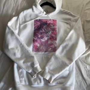 Vit hoodie med tryck - Säljer en vit hoodie från Drunk Elephant med ett unikt konstmotiv i rosa och lila nyanser på framsidan. Hoodien har en klassisk design med känguruficka och justerbar huva. Perfekt för en avslappnad stil!💗