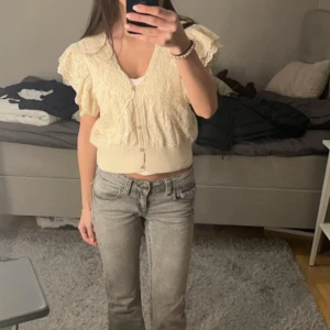 Vit  spetsblus från Zara - Säljer en söt beige spetsblus från Zara med korta volangärmar och v-ringning. Blusen har fina spetsdetaljer och knappar framtill. Perfekt för en romantisk look! Storlek m men passar mig som har xs