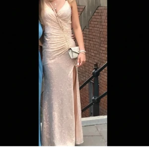Champagnefärgad glittrig långklänning - Säljer nu min beige/rosa balklänning från Lilly då den inte kommer till användning. Använd endast en gång. Den är uppsydd så den bara går ned till fötterna på mig som är 1,68. Skulle säga att den passar Xs-s. Säljer för 1700 + frakt.💗Skriv för fler bilder