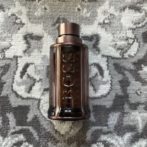 Hugo Boss The scent Absolute - Säljer en elegant parfymflaska från Hugo Boss, Bottled Absolute. Rymmer 100ml och är ca 60ml kvar i flaskan. Flaskan har en stilren design i mörkbrun nyans med metallisk glans och tydlig märkning. Perfekt för den som vill ha en sofistikerad doftupplevelse.