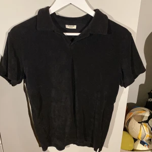 Svart pikétröja från Kappahl - Säljer en klassisk svart pikétröja från Kappahl. Tröjan har korta ärmar och en stilren krage. Perfekt för en avslappnad och stilren look. Frote piké, handduk piké. Storlek 158/164 men skulle säga att den passar upp mot 170