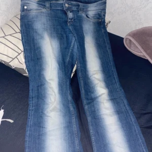 Blå jeans med slitningar - Snygga blå jeans med coola slitningar och en knappdetalj i midjan. Perfekta för en avslappnad stil. De har en klassisk passform och är tillverkade i jeansmaterial.