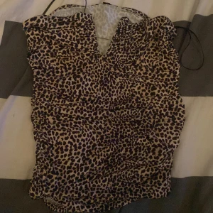 Leopardmönstrad topp - Säljer en snygg leopardmönstrad topp med v-ringning och smala axelband. Perfekt för en kväll ute eller när du vill sticka ut lite extra. Toppen har en åtsittande passform som framhäver figuren.