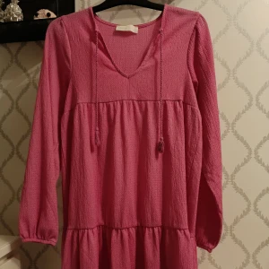 Rosa klänning  - Säljer en söt rosa klänning köpt på ullared med v-ringning och långa ärmar. Använd 1 gång!! Pris 100 kronor men det kan diskuteras!! 