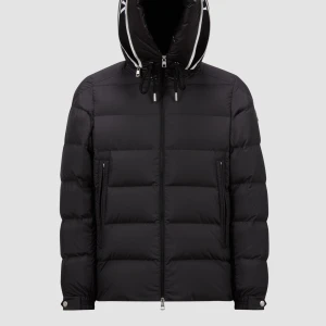 Svart pufferjacka från Moncler - Snygg svart pufferjacka från Moncler med dragkedja och huva. Jackan har en quiltad design och är perfekt för kyligare väder. Den har också praktiska fickor med dragkedjor.medium men passar som en stor