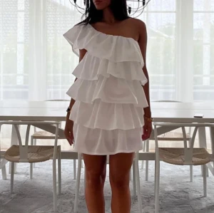 Vit axelbandslös klänning med volanger - Säljer denna otroliga klänningen från anielle! Helt oanvänd och perfekt till studenten och sommaren! Storlek xs men stretchig så passar även s.                                 nypris 1500 kr