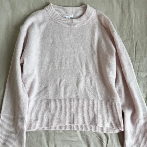Ljusrosa stickad tröja - Mysig ljusrosa stickad tröja med ribbade detaljer vid ärmslut och nederkant. Perfekt för kyliga dagar och ger en stilren look. Passar bra till både jeans och kjol.