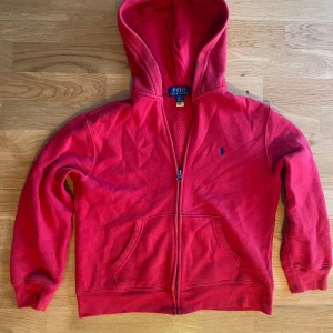 Röd hoodie från Polo Ralph Lauren - Säljer en snygg röd hoodie från Polo Ralph Lauren med dragkedja och huva. Tröjan har långa ärmar och en klassisk logga på bröstet. Den har blivit använd ca 5 gånger Perfekt för en avslappnad stil. Hör av dig vid intresse! 🔥