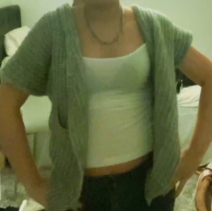 Grå stickad kofta - Säljer en mysig grå stickad kofta med korta ärmar. Perfekt för lager-på-lager och ger en avslappnad look. Passar bra till både jeans och kjol.