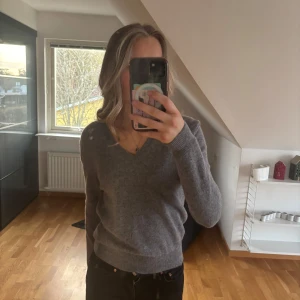 Grå tröja från United Colors of Benetton - Säljer en stilren grå tröja från United Colors of Benetton. Tröjan har en v-ringad design och långa ärmar, perfekt för en avslappnad look. Passar bra till både jeans och kjol.