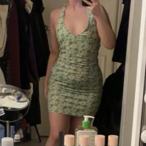 Grön mönstrad klänning - Snygg grön klänning med ett subtilt mönster. Den är ärmlös och har en tight passform som framhäver figuren. Perfekt för sommarens varma dagar.