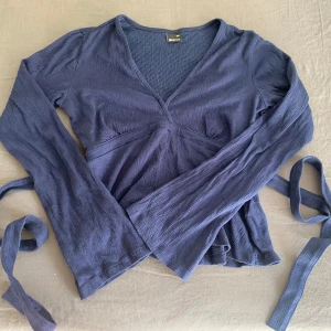 Mörkblå topp från Gina Tricot - Toppen har en v-ringad design och vida ärmar. använd 2-3 gånger 