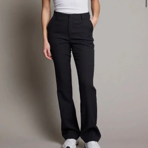  kostymbyxor från Bik Bok - Snygga svarta kostymbyxor från Bik Bok med medelhög midja. Byxorna har en klassisk design med en rak passform och är perfekta för en stilren look. Storlek 36 i modellen Vilma.