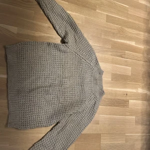 Beige stickad tröja - Säljer en mysig beige stickad tröja med ett fint texturerat mönster. Tröjan har långa ärmar och en ribbad krage som ger extra värme. Aldrig använd. Perfekt för kyliga dagar!