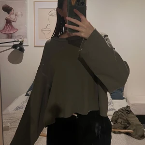 Olivgrön croppad tröja från Zara - Säljer en olivgrön croppad tröja från Zara. Tröjan har långa ärmar och en avslappnad passform. Bra skick! 